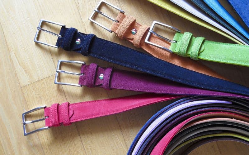Plusieurs ceintures de couleur différente posées sur un parquet.